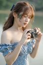 Woman in Blue and White Floral Off Shoulder Dress Holding Camera