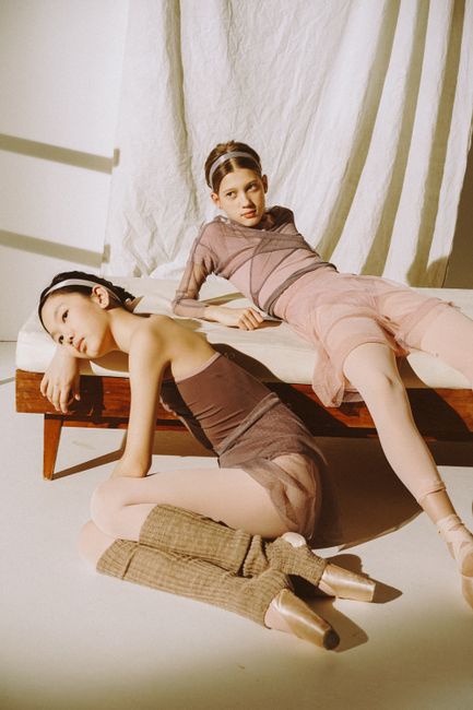 Two ballet dancers posing gracefully on a bed, embodying artistic minimalism.