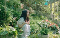 一名女子在花园里，享受着被郁郁葱葱的绿植和鲜花包围的宁静时刻