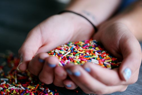 Free A close-up of hands holding a handful of colorful sprinkles over a dark surface. Stock Photo