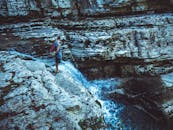 一名孤独的徒步旅行者站在悬崖边，俯瞰瀑布，感受着大自然的宁静