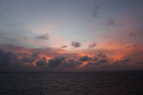 Free A stunning sunset with dramatic clouds over a calm ocean, creating a serene and picturesque view. Stock Photo