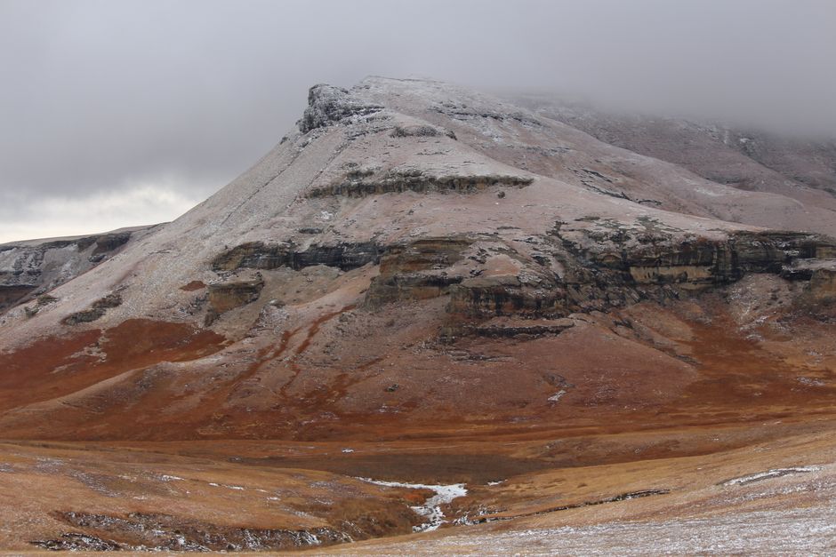 A scenic view of a snow-dusted mountain with cloudy skies, capturing the beauty of nature.