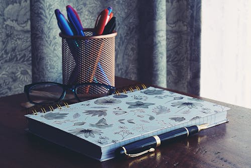 Free Close-Up Photography of Notebook Near Pens Stock Photo