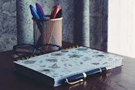 Close-Up Photography of Notebook Near Pens