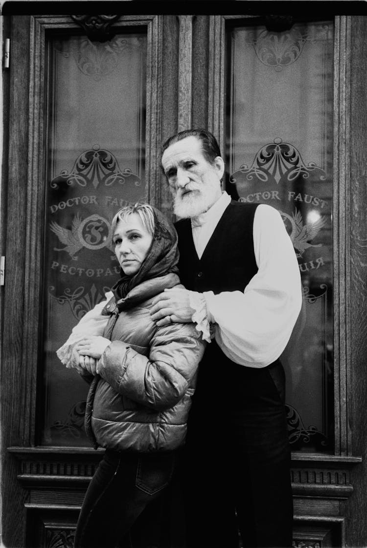 Old Bearded Man And Woman Standing In Front Of Stylish Door