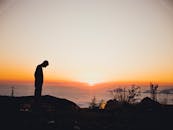 山上的日落，充满活力，映照着一个人的轮廓，捕捉到了宁静的景色