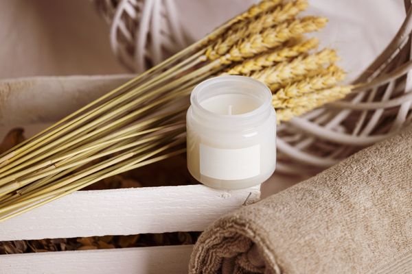 White candle with dried wheat and a folded towel