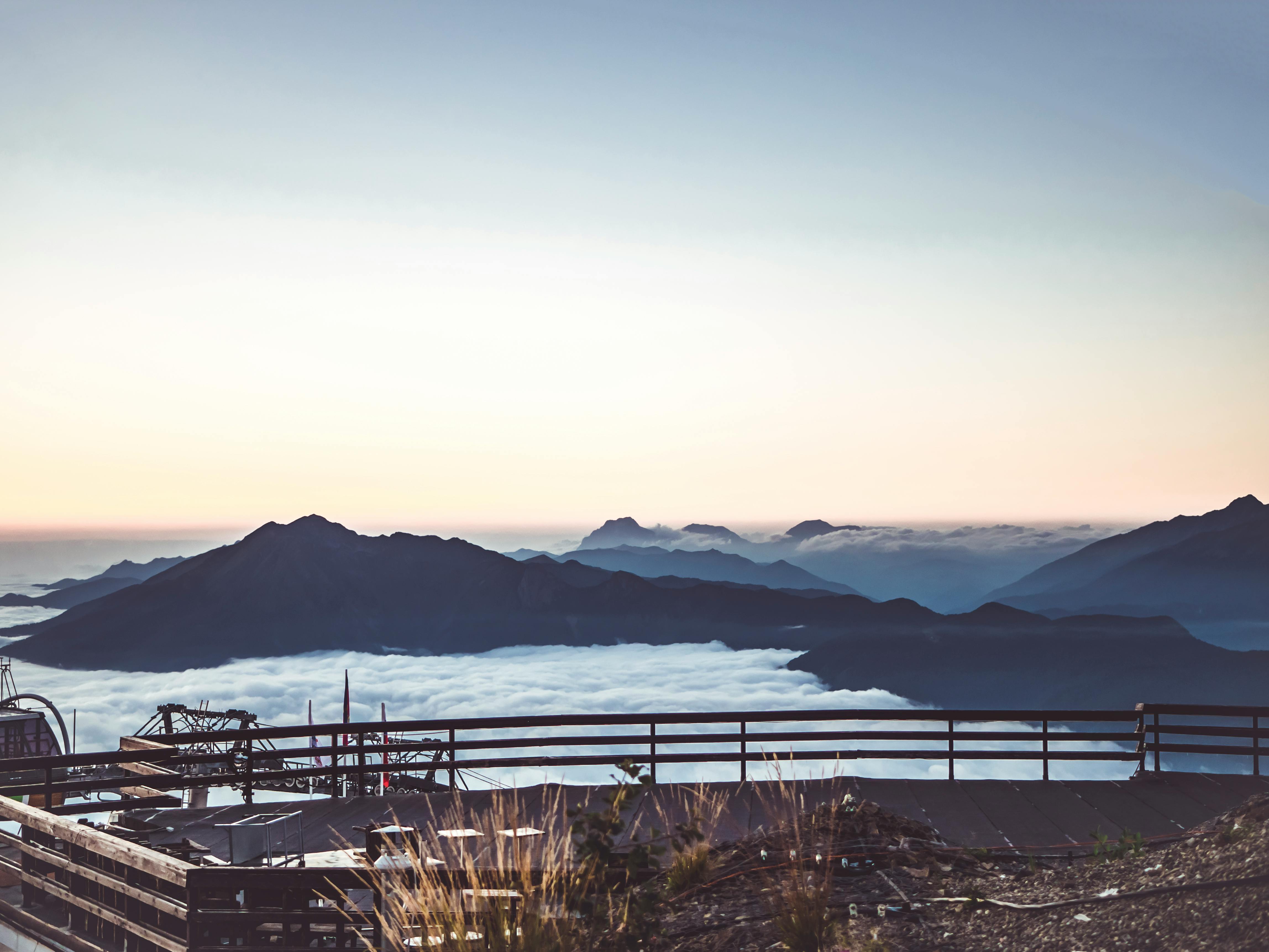 日出时分，薄雾笼罩的山谷与迷人的山脉景色尽收眼底，前景处可见木栏杆
