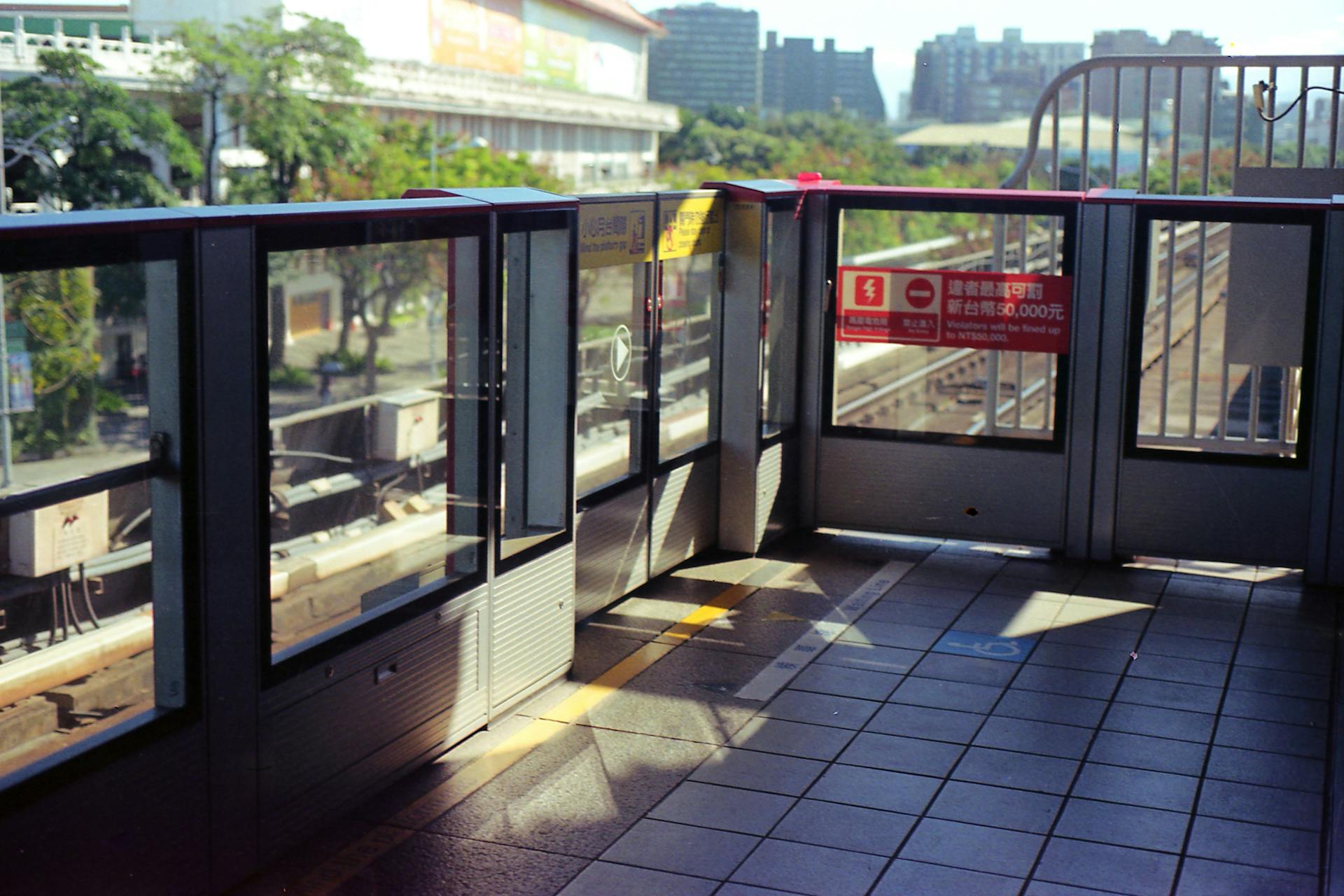 Bright Taipei Metro station platform with safety gates and vibrant urban backdrop.