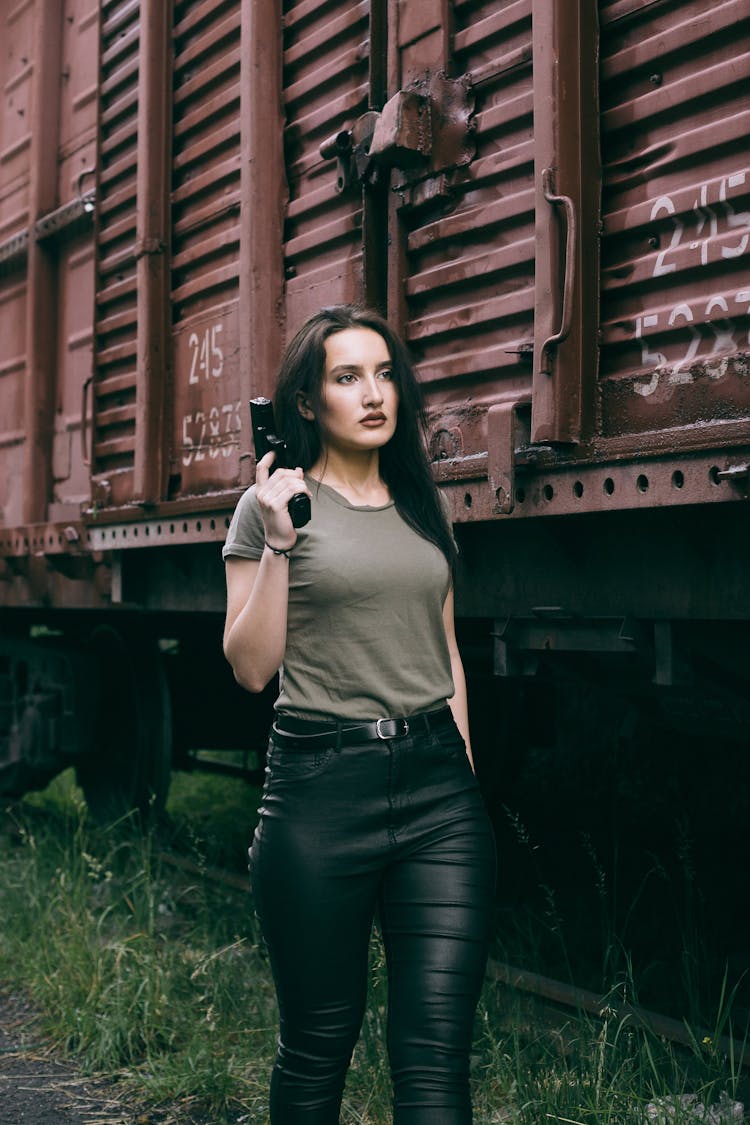 Woman Holding A Gun Walking Beside The Train