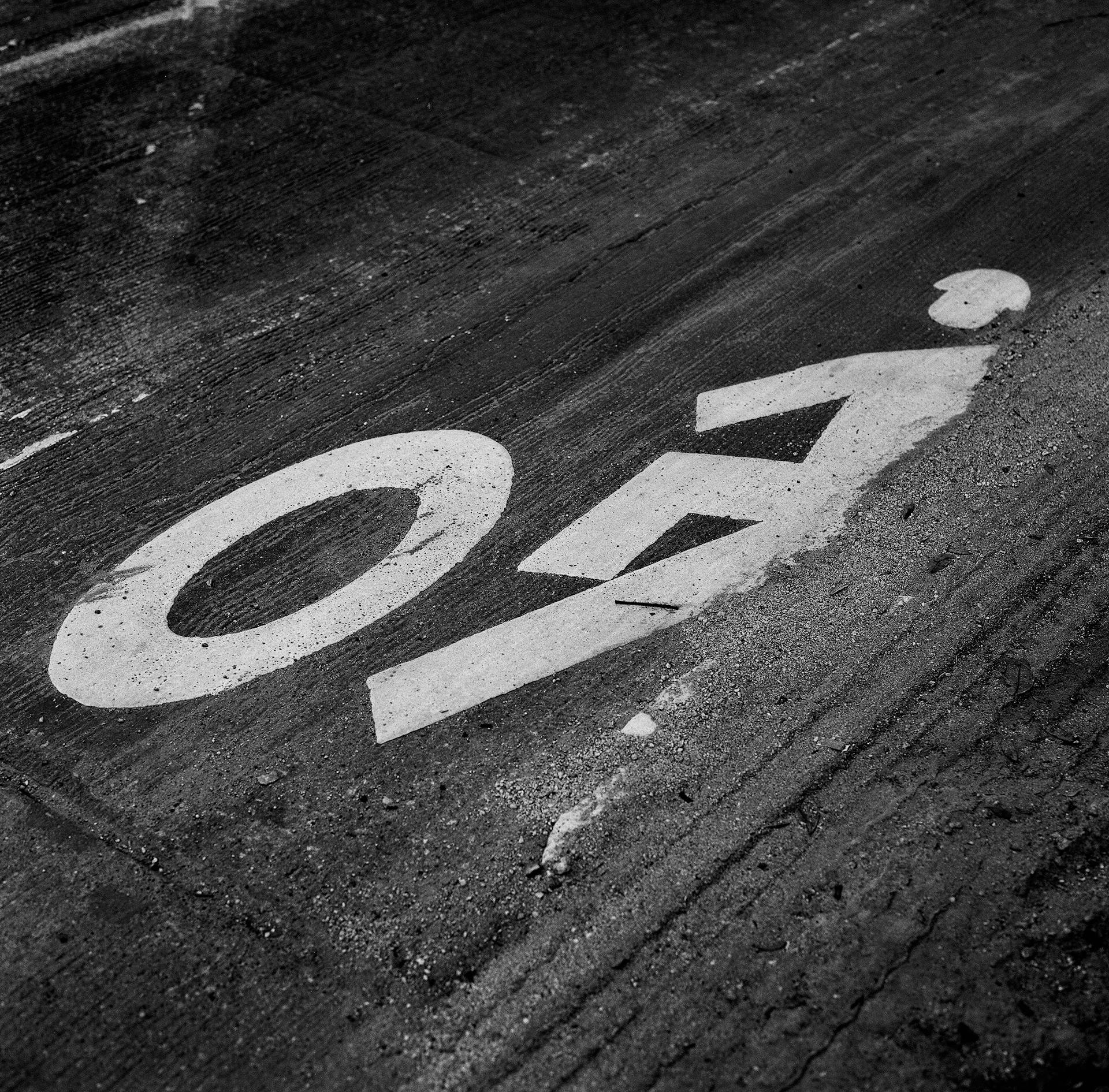 A close-up shot of a bicycle lane sign on an asphalt road in black and white, symbolizing safety and guidance.