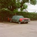 A Parked Red Car Covered with a Tarpaulin