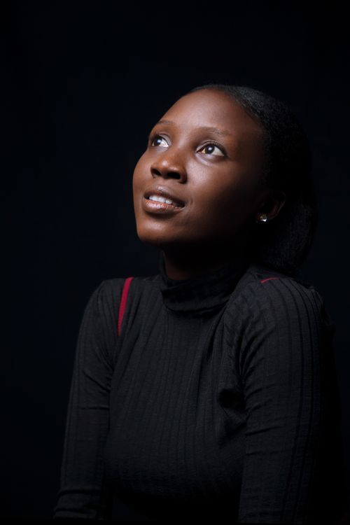 Free Studio portrait of a smiling woman looking up, set against a dark background. Captures elegance and simplicity. Stock Photo