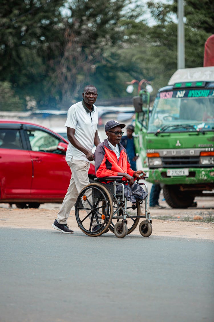 Man Pushing An Elderly Man In A Wheelchair