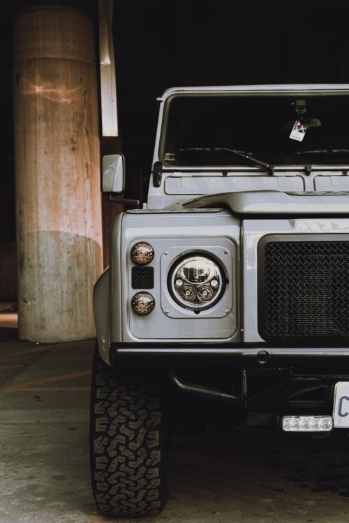 Free Close-up of a restored vintage Land Rover Defender parked in an urban environment with unique lighting. Stock Photo