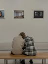 A Couple Sitting Together on a Bench inside a Museum