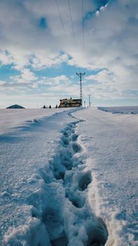A snowy path leads to a solitary building under a winter sky.