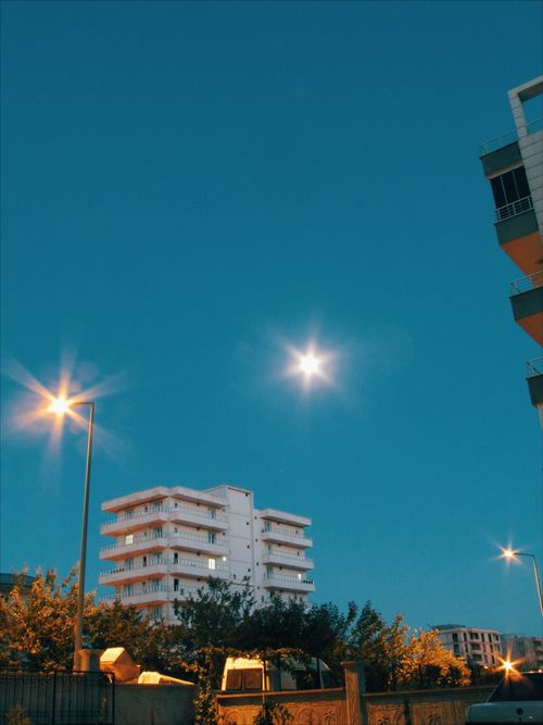 Free A low-angle view of a building and street lamps under the moonlit dusk sky. Stock Photo