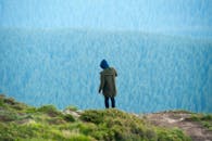 Person in Green Jacket Standing on Cliff