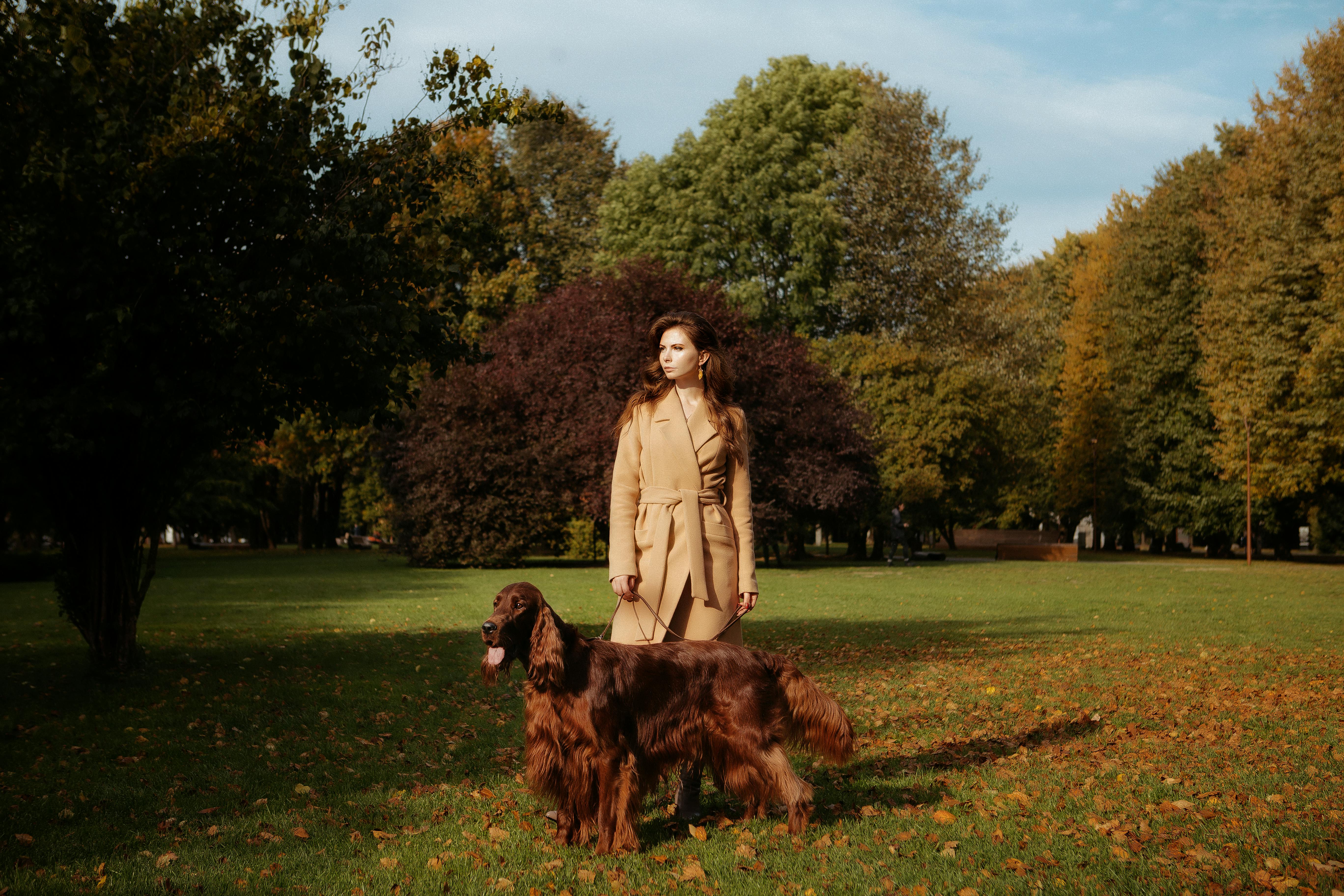 Woman in a Coat on a Walk with her Dog in the Park