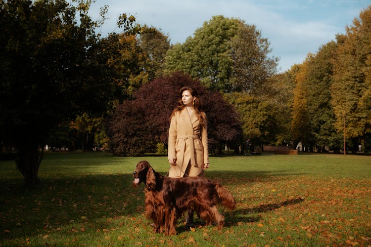 Woman In A Coat On A Walk With Her Dog In The Park