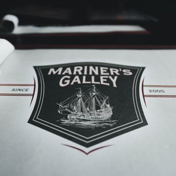 Close-up of Mariner's Galley logo featuring a nautical design with a galleon ship.