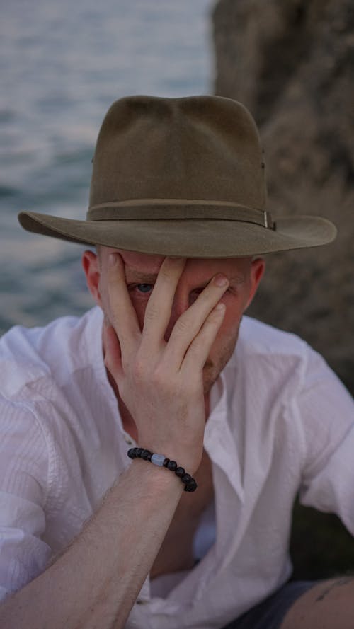 남자, 모자, 손으로 얼굴 가리기의 무료 스톡 사진