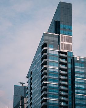 Contemporary glass skyscraper in Calgary against a cloudy sky, showcasing urban architecture.