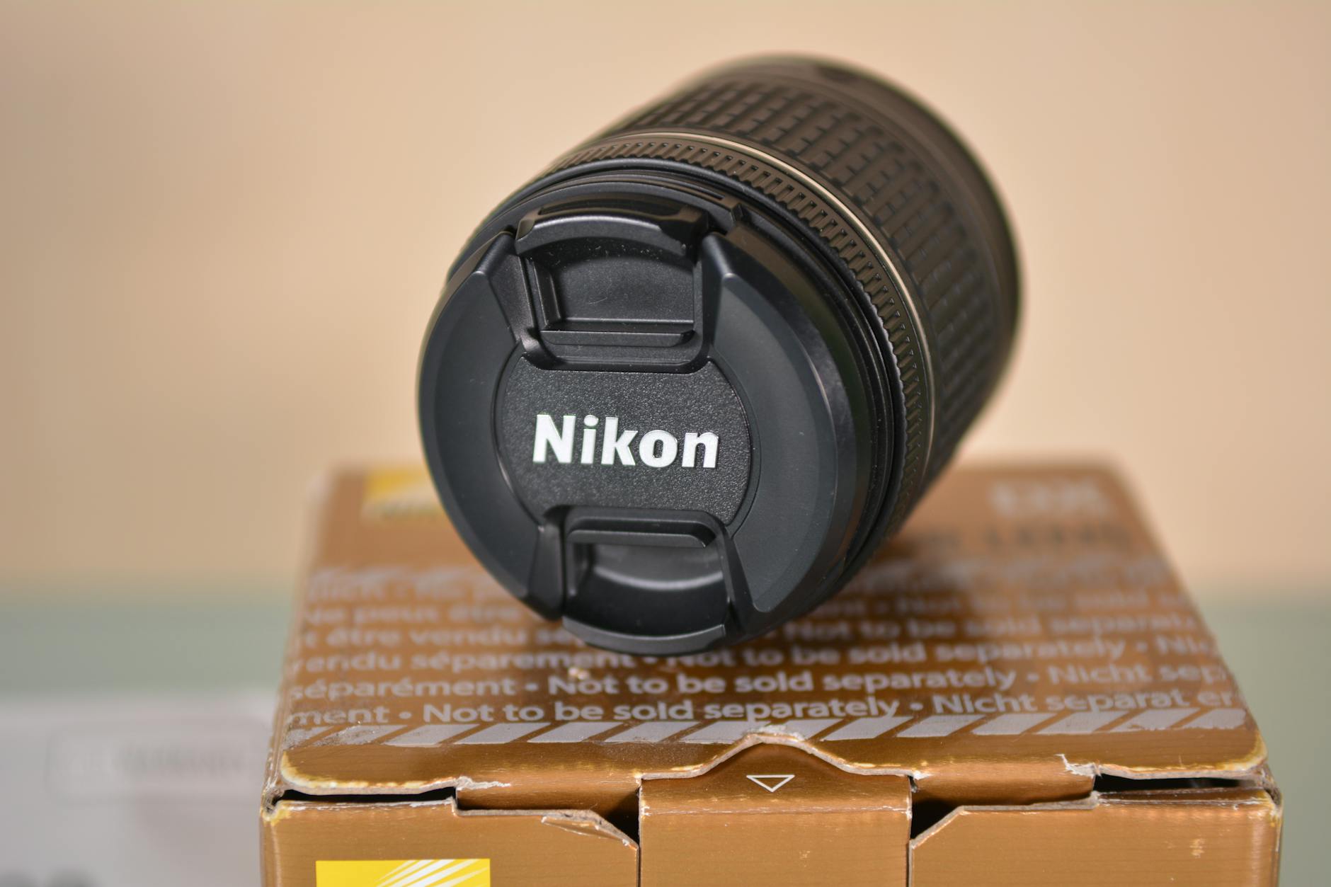 Close-up of a Nikon camera lens resting on a box, showcasing optical technology.