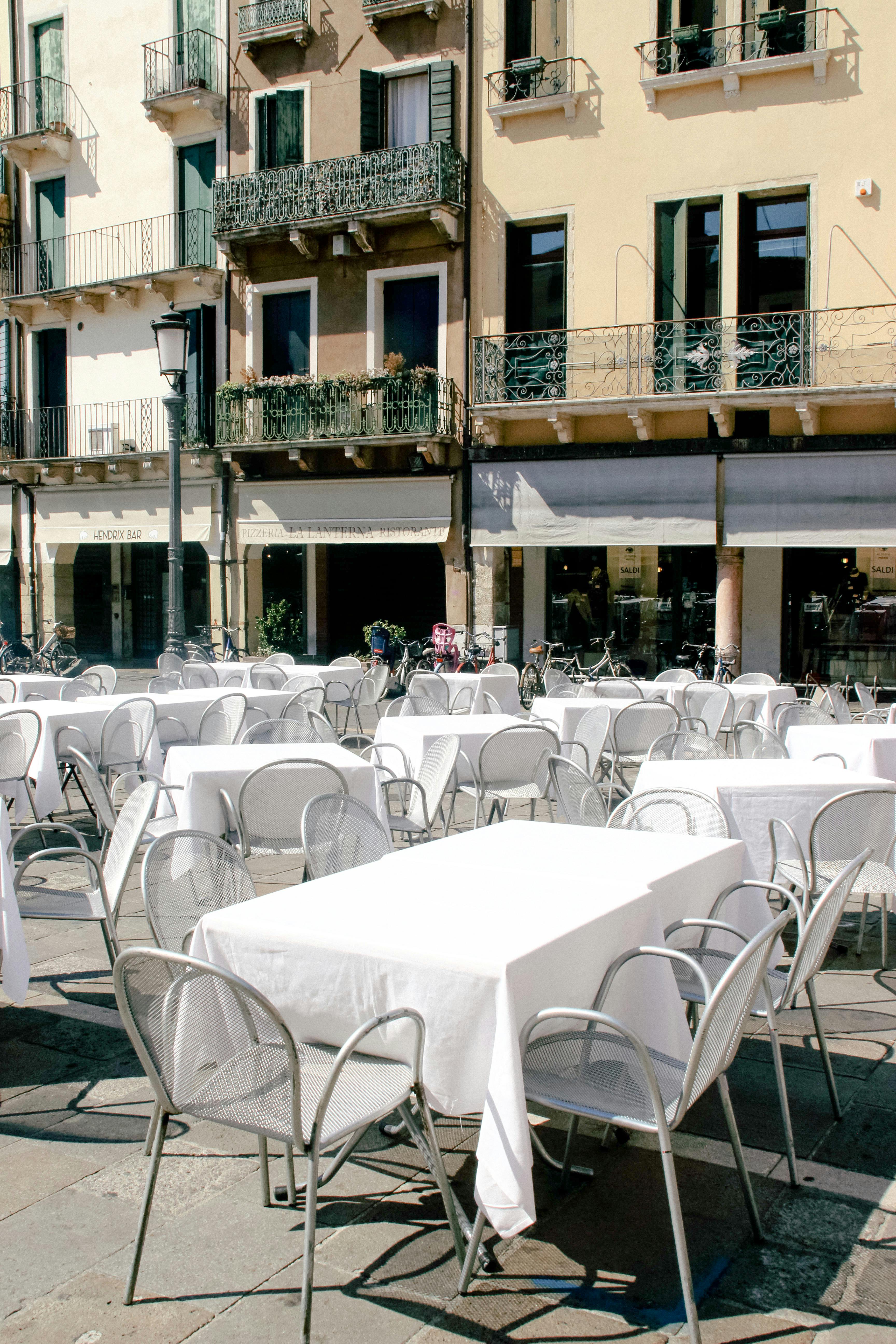 Empty outdoor dining area with white tablecloths in Venice, Italy, ready for a sunny day event.