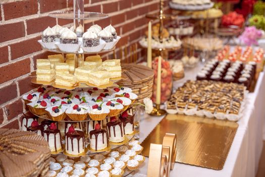 A lavish dessert table with various pastries and cakes at a festive indoor event.