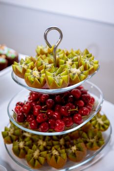 Vibrant tiered display of sliced kiwis and fresh cherries for a delicious, healthy dessert.