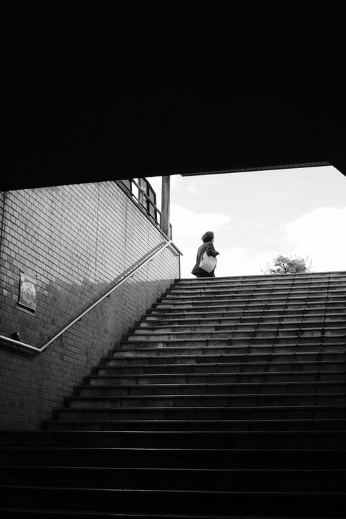 Free A lone figure ascends a staircase in a striking black and white city setting. Stock Photo