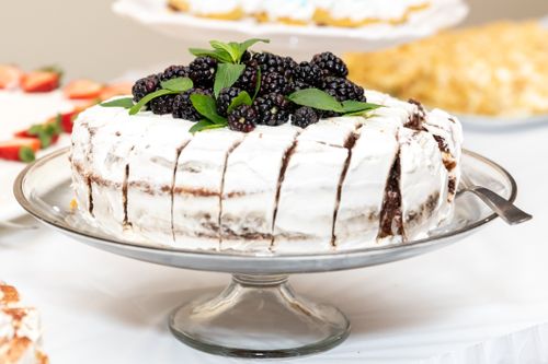 Free Sliced cake with blackberries and mint on a cake stand, ready to serve. Stock Photo