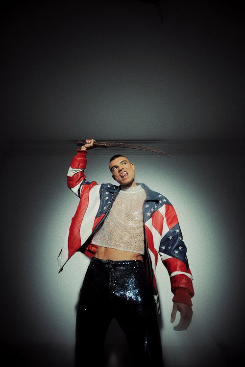 Free Fashionable male model posing with American flag jacket in dramatic studio lighting holding a knife. Stock Photo