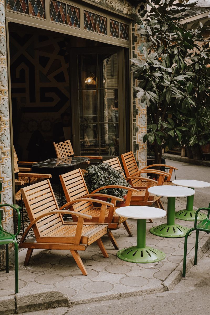 Wooden chairs and round coffee tables on the sidewalk outside the cafe