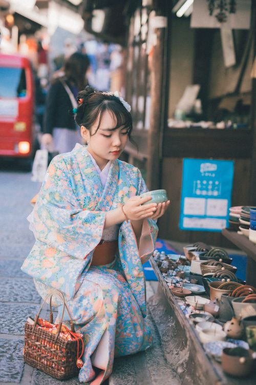 Free A Japanese woman wearing a kimono selects pottery in a traditional shop. Stock Photo