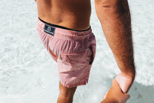 A man in swimwear holds hands while strolling in clear tropical waters.