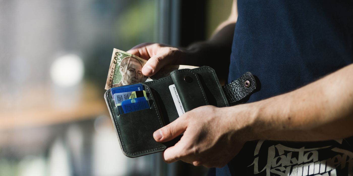 Close-up of a man holding a wallet with cash and credit cards, indoors.
