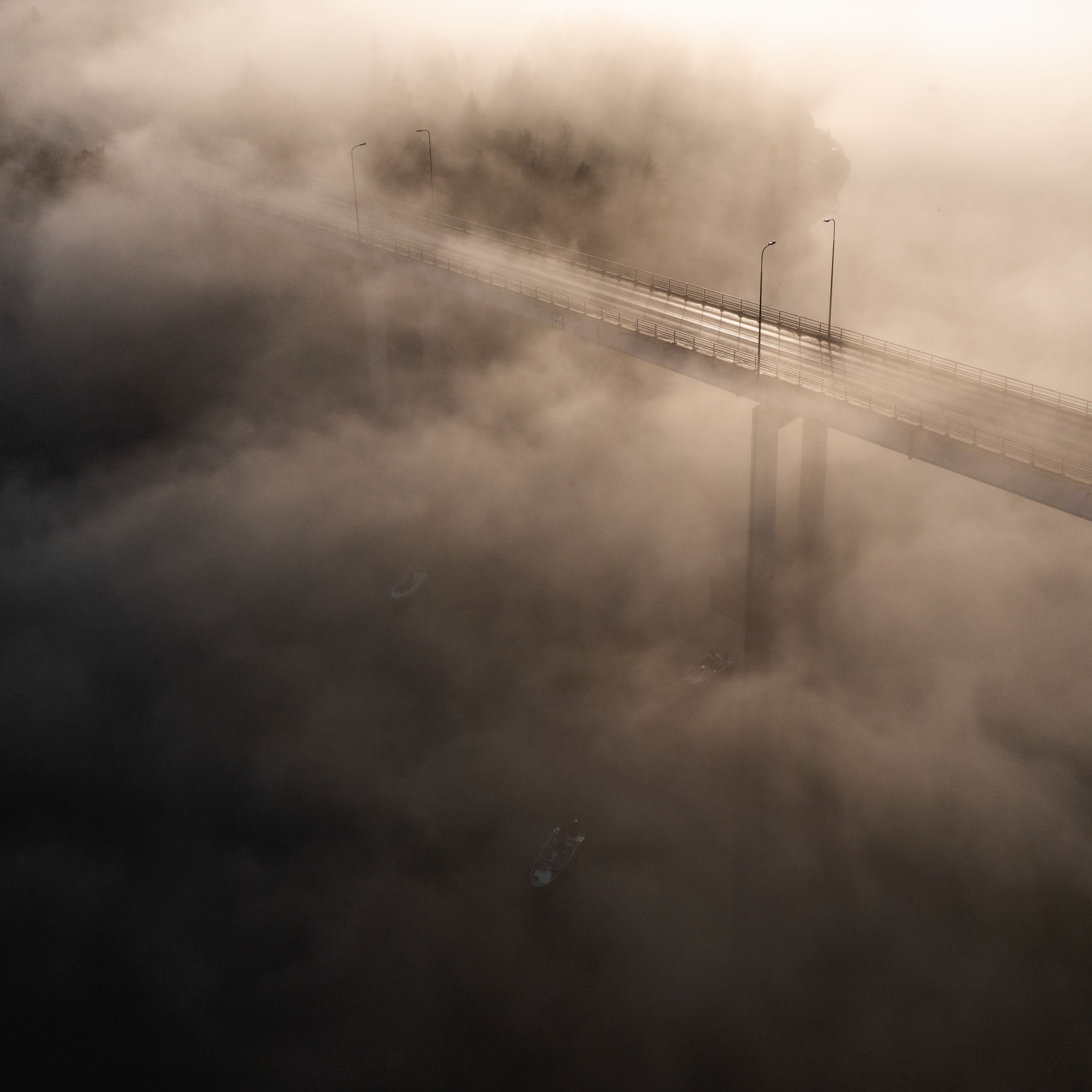 Aerial view of a bridge shrouded in fog in Rymättylä, Finland, showing serene mystery.