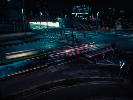 A dynamic night scene in Milan showing light trails from cars at a busy intersection.