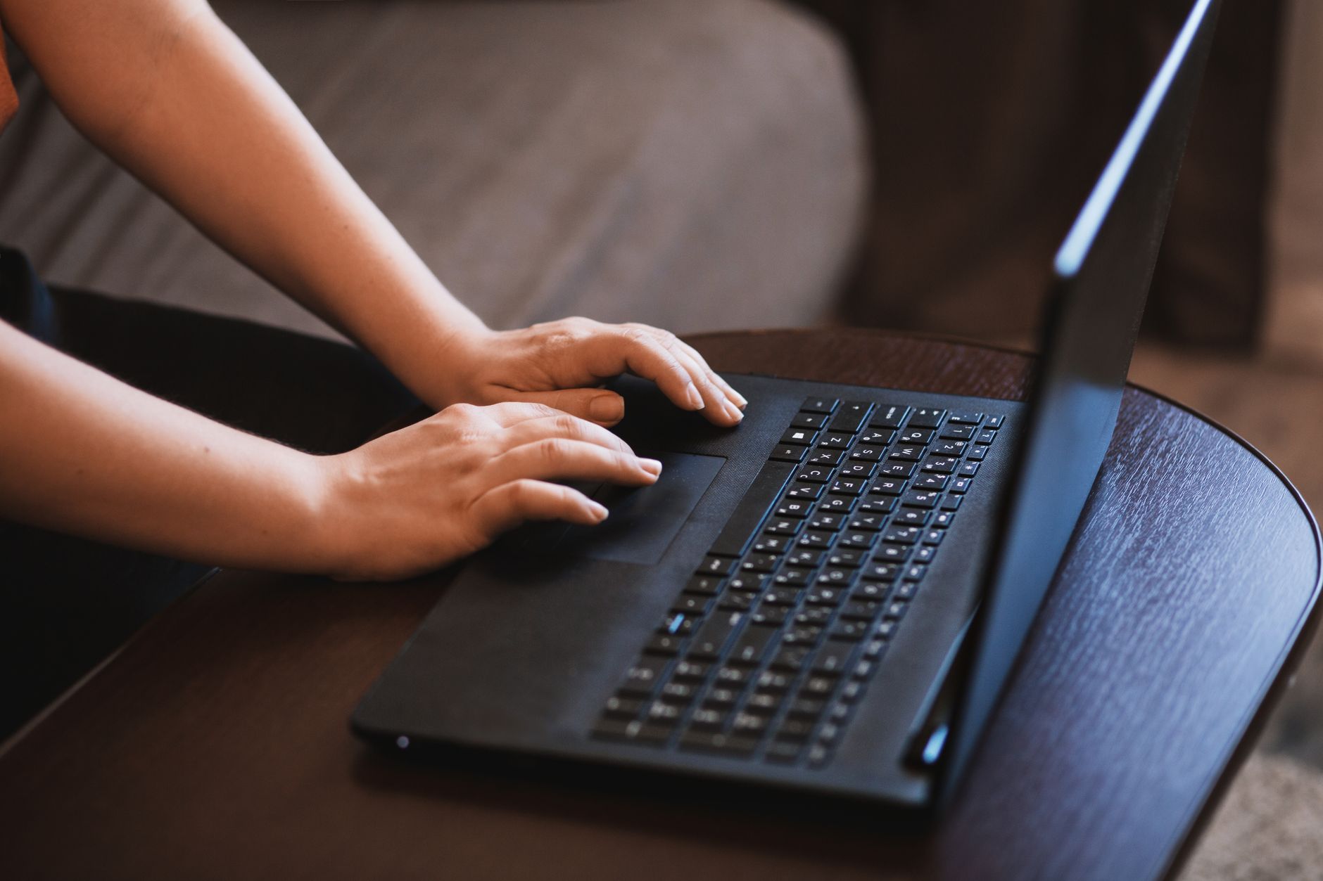 A close-up image of hands typing on a laptop, emphasizing technology and work.