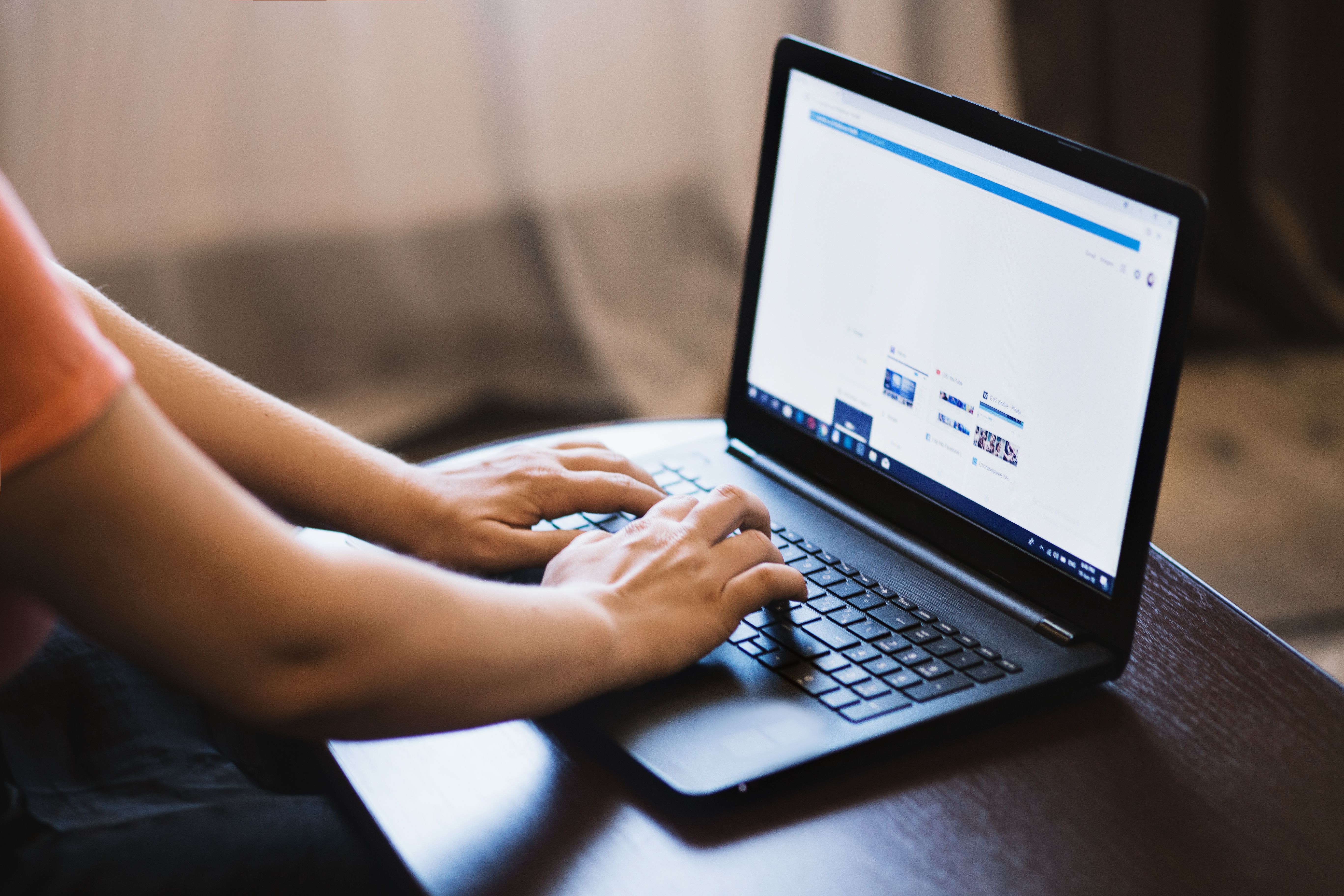 A close-up shot of a person's hands typing on a laptop keyboard, with soft natural light illuminating the keys and fingers, conveying focus and productivity.