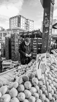 Black and white photo of an elderly merchant selling potatoes at a Kayseri market.