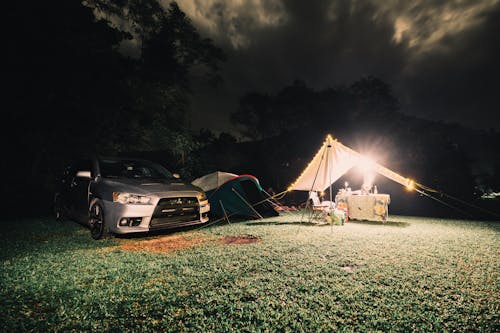 A Silver Car and Tents on a Camping Site at Night