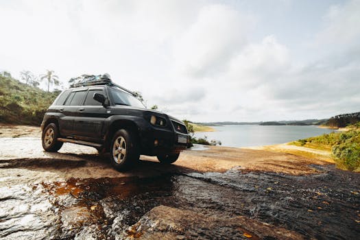 An SUV parked on rugged terrain with a scenic lake view, perfect for off-road adventures.