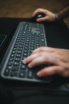 Hands typing on a keyboard with a focus on the movement and technology use.