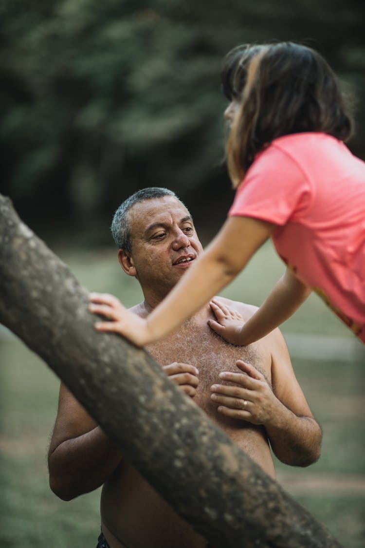 A Father Helping Daughter Climb A Tree Trunk
