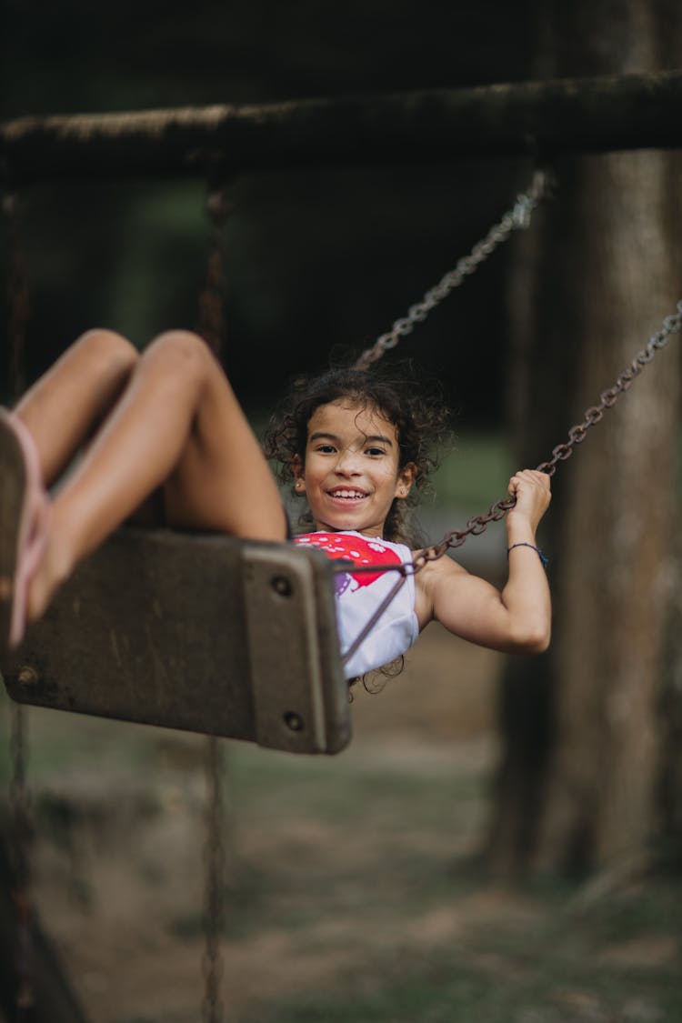 Smiling Girl Swinging On A Swing